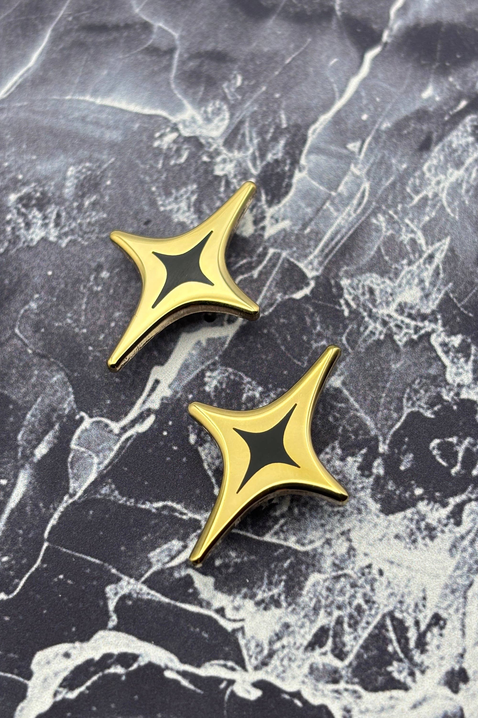 Gold and black star-shaped pins on a marble surface