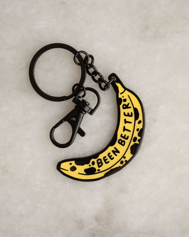Enamel and metal keychain in the shape of a bruised banana featuring the phrase "been better"