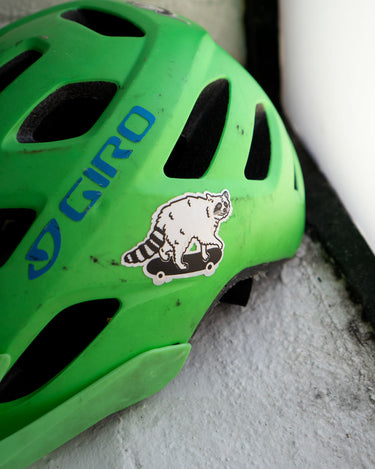 Reflective sticker of a cute raccoon on a skateboard shown on a kids bike helmet