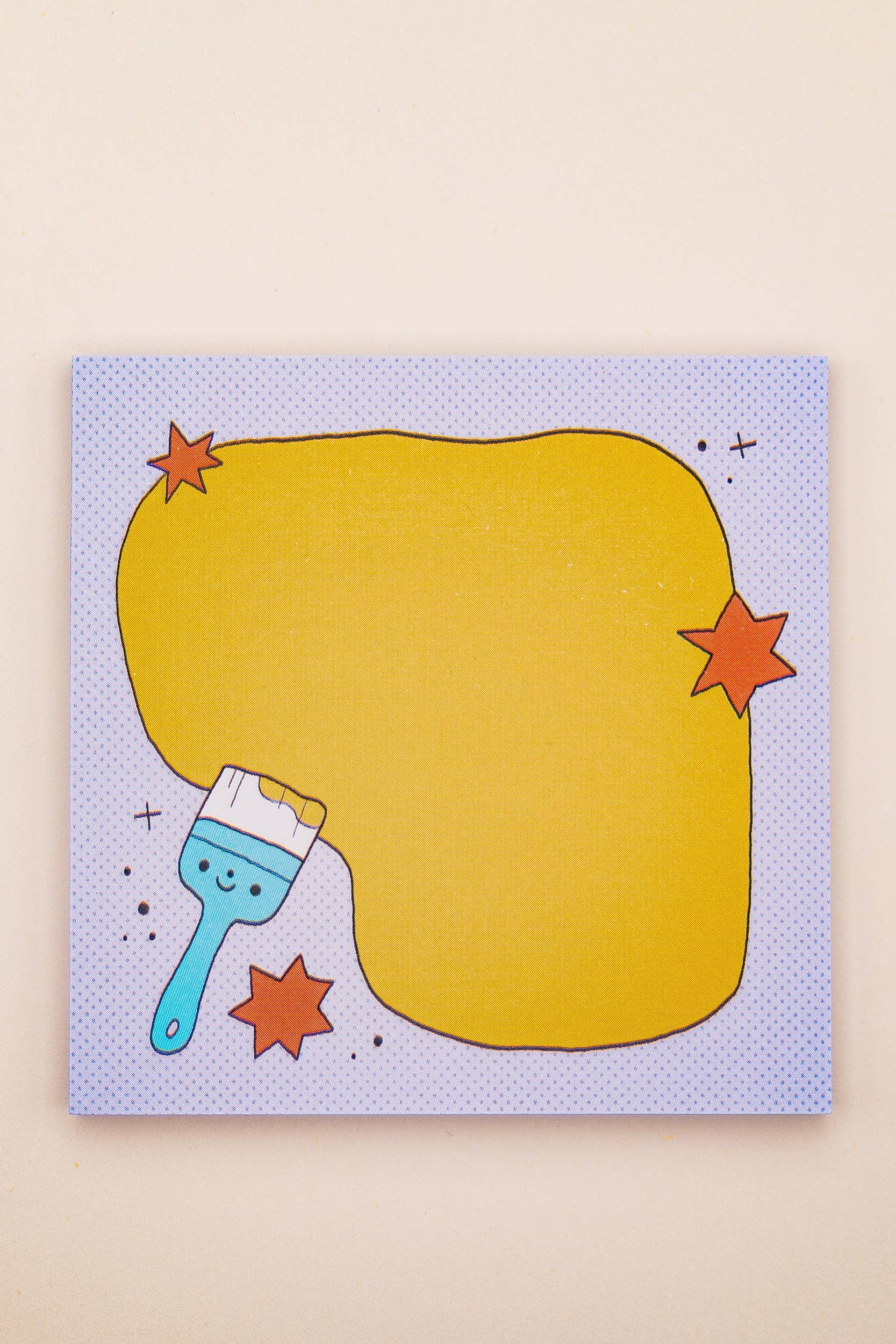 Pad of sticky notes with a blue brush and yellow oval on a beige background