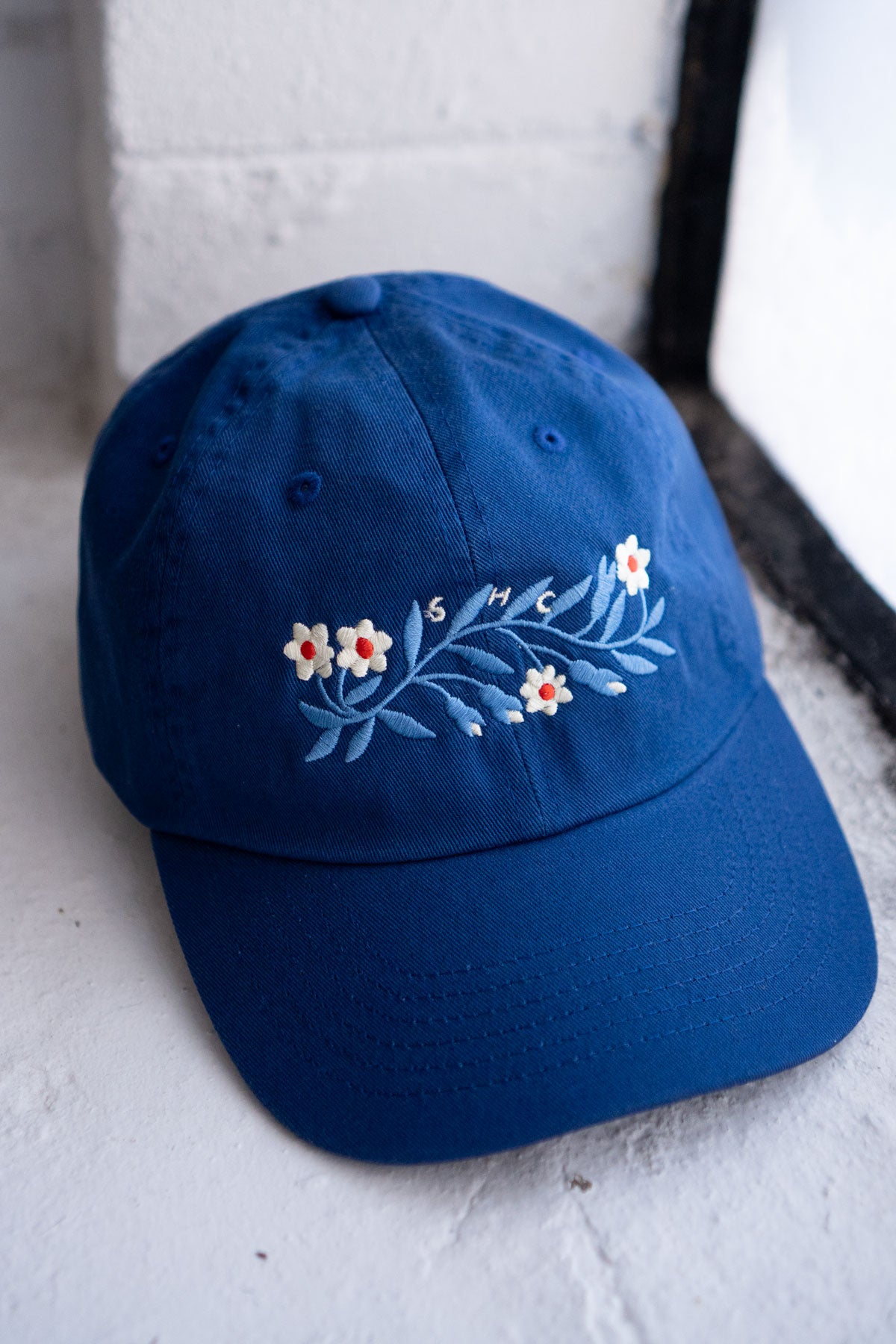 Blue cap with floral embroidery on a textured surface